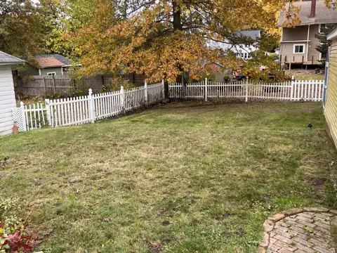 The same backyard lawn cleared of leaves beside a brick patio