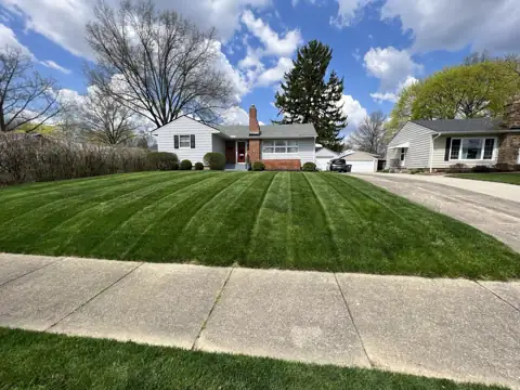 Fresh mowing stripes leading toward a home and driveway