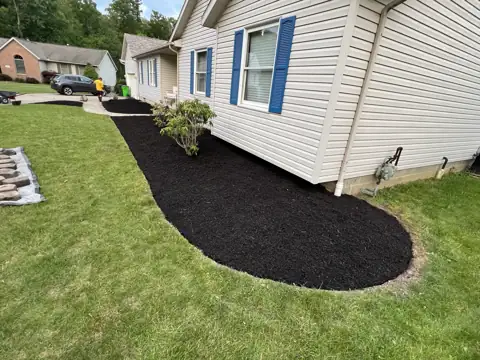 A refreshed landscape bed with dark mulch and a clean edge beside the same home
