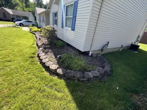 An existing bed with stone edging beside a home before refresh