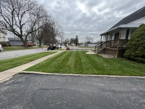 A freshly mowed lawn with stripes beside a sidewalk