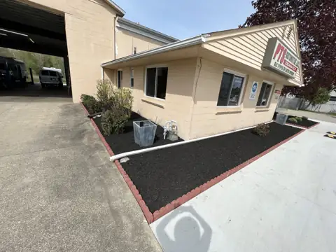 A dark mulched bed along a building and driveway