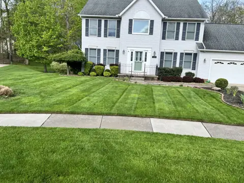 A striped lawn in front of a two-story home