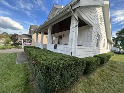 Trimmed hedges along a porch viewed from the lawn