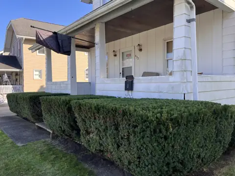 A level hedge line in front of a covered porch